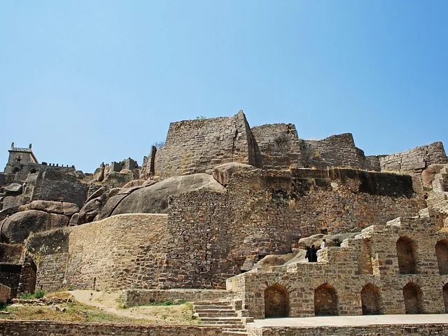 Stone walls and structures of Golconda Fort under a clear blue sky