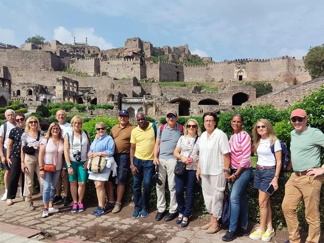 A large tour group posing in front of the Golconda Fort ruins