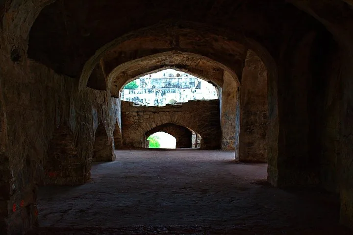 Looking through a dark, arched stone corridor at Golconda Fort